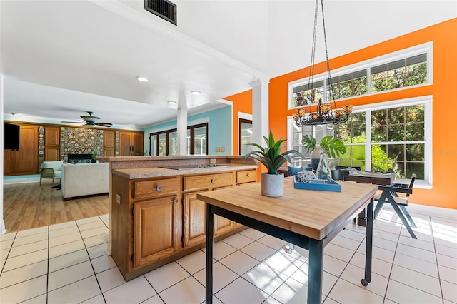 kitchen featuring ceiling fan, a stone fireplace, pendant lighting, black electric stovetop, and light wood-type flooring