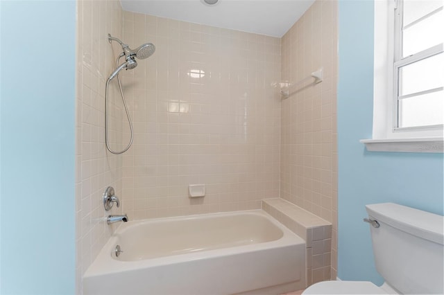 bathroom featuring tiled shower / bath combo and toilet