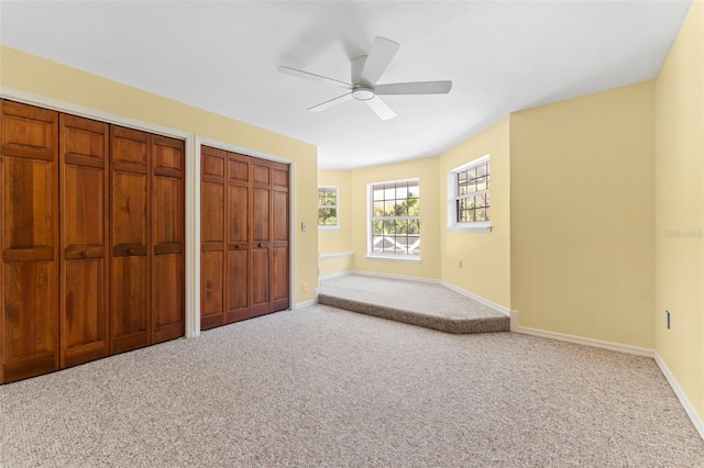 unfurnished bedroom with carpet flooring, multiple closets, and ceiling fan