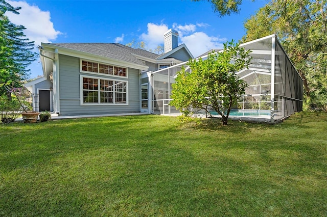 rear view of property with glass enclosure and a lawn