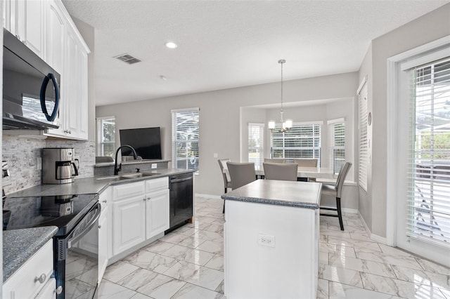 kitchen with backsplash, black appliances, white cabinets, a kitchen island, and decorative light fixtures