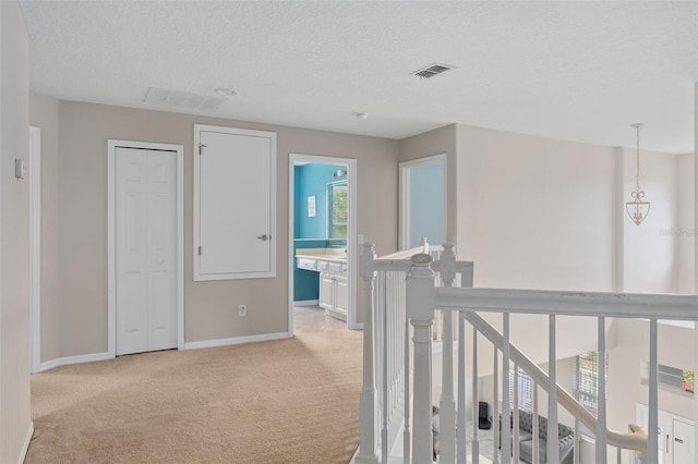 hallway featuring light colored carpet and a textured ceiling