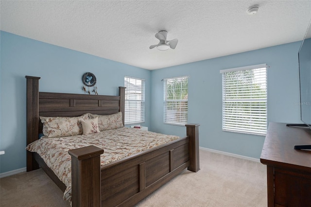 bedroom featuring light carpet, multiple windows, and a textured ceiling