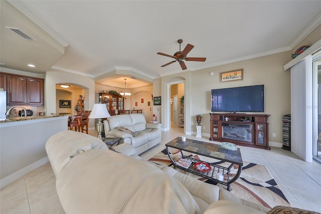 living room featuring ceiling fan with notable chandelier, light tile patterned flooring, and ornamental molding