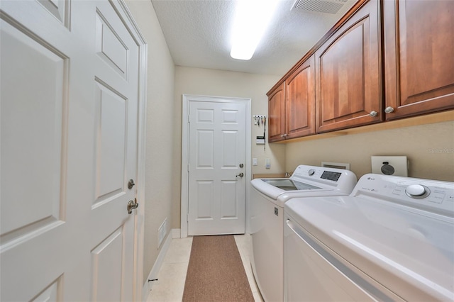 laundry area featuring cabinets, a textured ceiling, washing machine and dryer, and light tile patterned floors