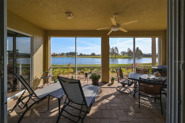 sunroom with a water view and ceiling fan