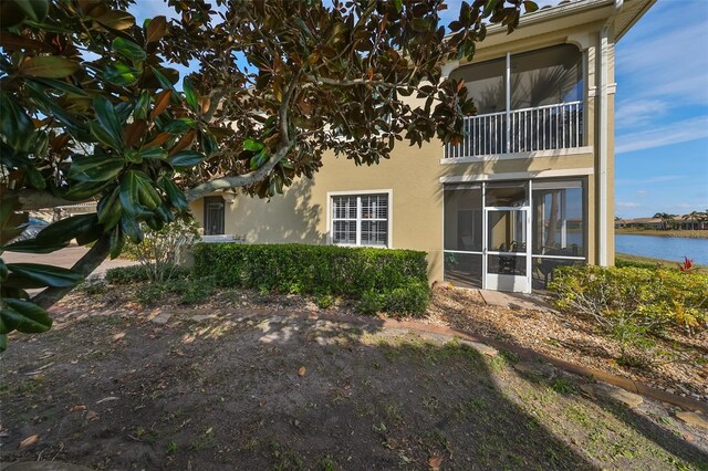 rear view of property with a water view and a sunroom