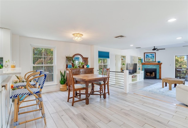 dining room with a healthy amount of sunlight, ceiling fan with notable chandelier, and light wood-type flooring