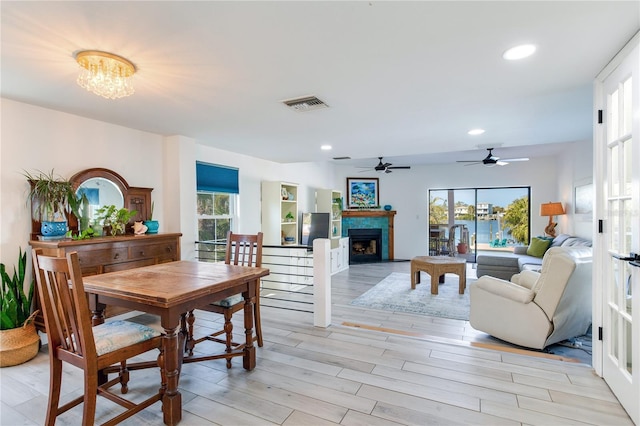 dining space with a wealth of natural light, ceiling fan with notable chandelier, and light wood-type flooring