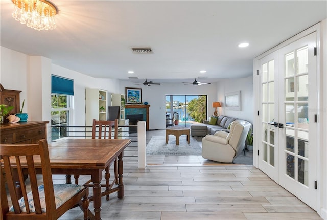 dining space featuring french doors, light hardwood / wood-style floors, and ceiling fan with notable chandelier