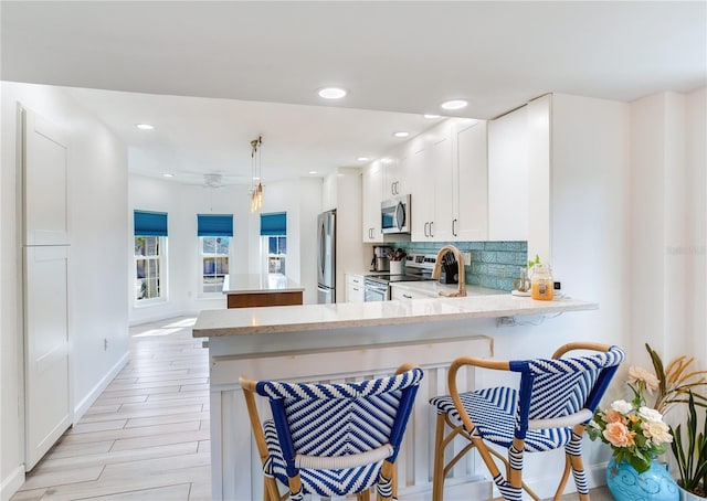 kitchen with white cabinetry, kitchen peninsula, a breakfast bar area, and appliances with stainless steel finishes