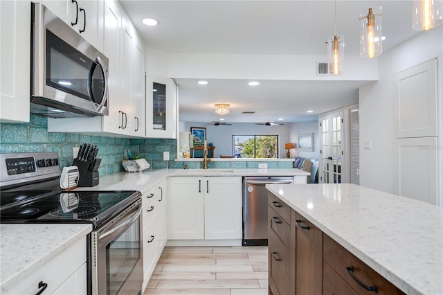 kitchen with light stone countertops, appliances with stainless steel finishes, ceiling fan, sink, and white cabinetry