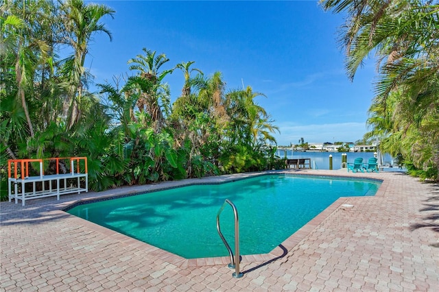 view of pool featuring a water view and a patio