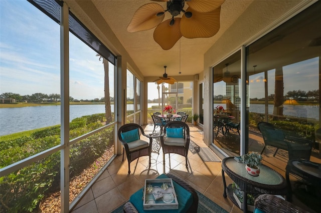 sunroom with ceiling fan and a water view