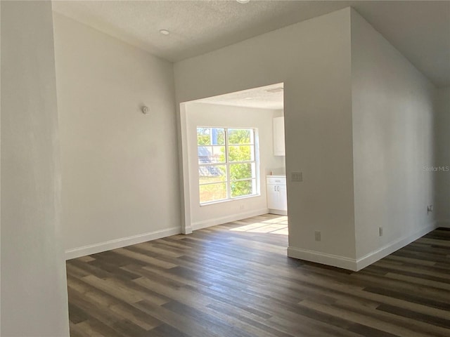 unfurnished room featuring dark wood-type flooring and a textured ceiling