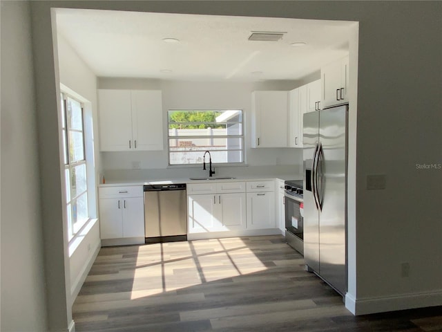 kitchen with hardwood / wood-style flooring, sink, white cabinets, and appliances with stainless steel finishes