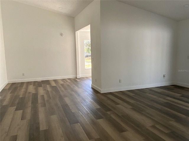 empty room with dark hardwood / wood-style flooring and lofted ceiling