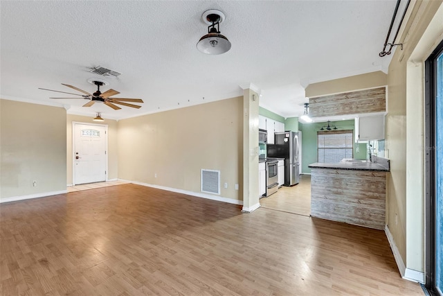 unfurnished living room with a textured ceiling, light hardwood / wood-style floors, ceiling fan, and ornamental molding