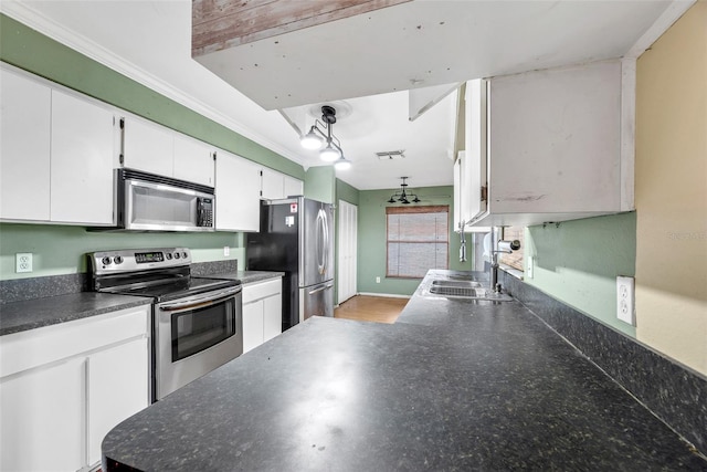 kitchen featuring sink, hanging light fixtures, ornamental molding, white cabinetry, and stainless steel appliances