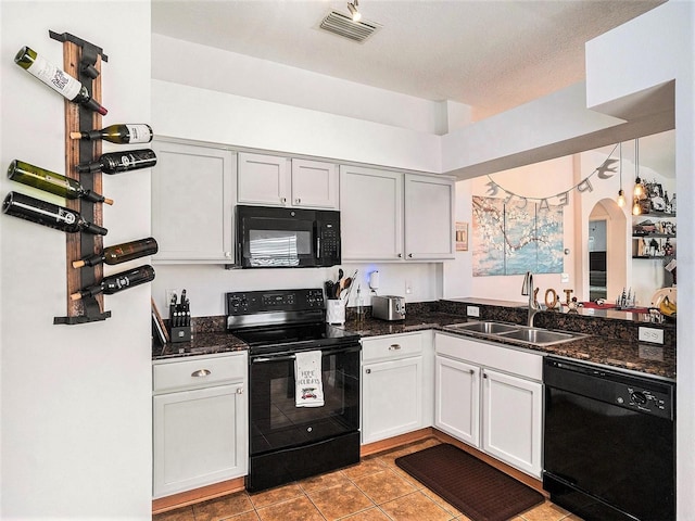 kitchen with dark stone counters, a textured ceiling, sink, black appliances, and white cabinets