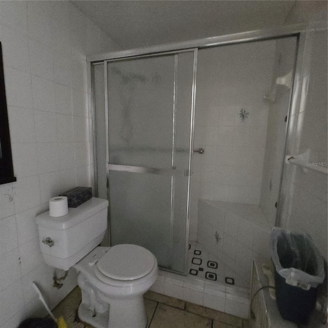 bathroom featuring tile patterned floors, toilet, tile walls, and walk in shower