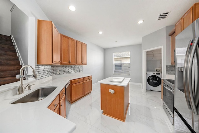 kitchen featuring sink, a center island, stainless steel appliances, tasteful backsplash, and washer / dryer