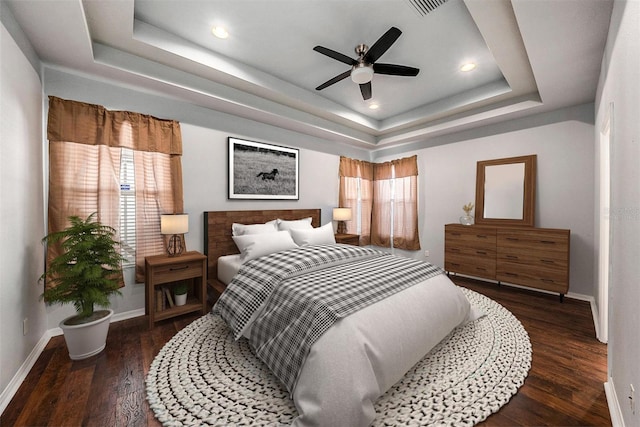 bedroom with dark hardwood / wood-style flooring, a raised ceiling, and ceiling fan