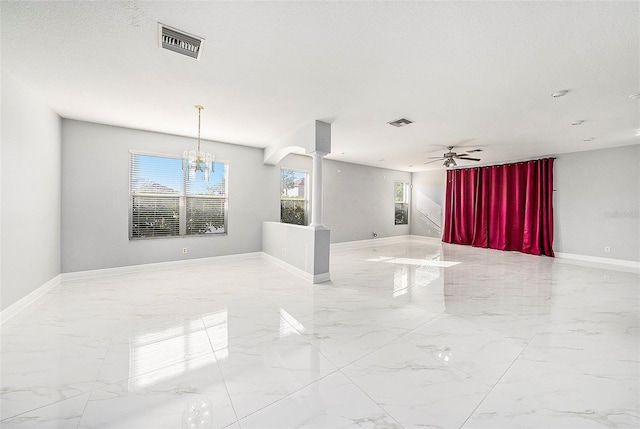 empty room featuring ceiling fan with notable chandelier and a textured ceiling