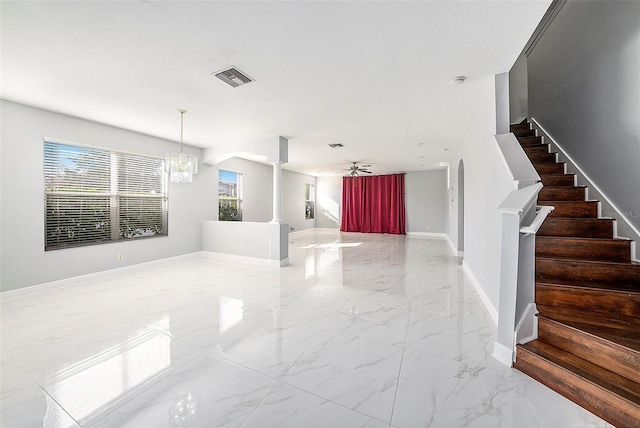 foyer entrance featuring ornate columns and ceiling fan with notable chandelier