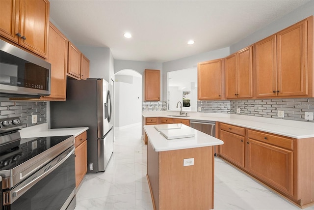 kitchen with tasteful backsplash, sink, a center island, and appliances with stainless steel finishes