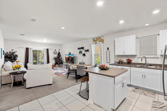 kitchen with white cabinets, light carpet, a center island, and sink