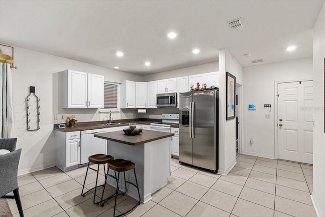 kitchen featuring sink, stainless steel appliances, a kitchen island, a breakfast bar, and white cabinets