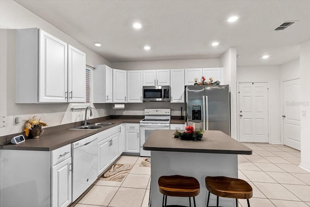 kitchen with white cabinetry, sink, a center island, a kitchen bar, and appliances with stainless steel finishes