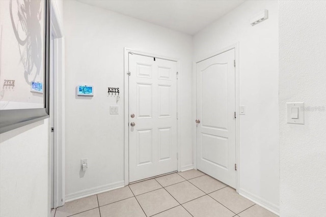 foyer entrance with light tile patterned floors and baseboards