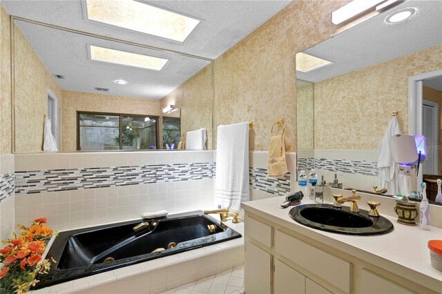 bathroom featuring vanity, tile patterned floors, a skylight, a relaxing tiled tub, and a textured ceiling