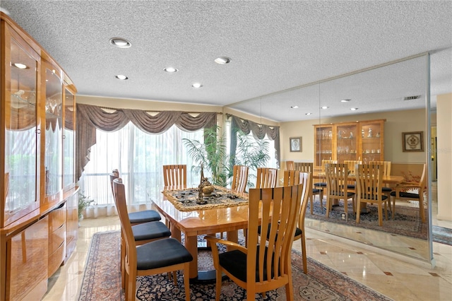 tiled dining area with a wealth of natural light and a textured ceiling