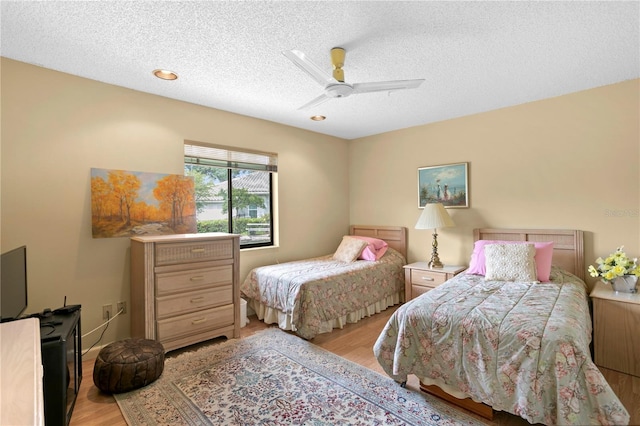 bedroom featuring ceiling fan, light hardwood / wood-style flooring, and a textured ceiling