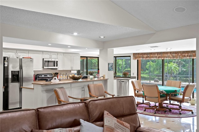 kitchen with a textured ceiling, white cabinets, stainless steel appliances, and light tile patterned floors