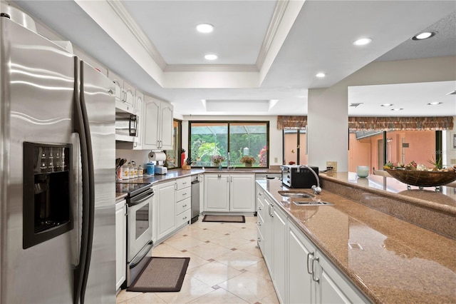 kitchen featuring sink, stainless steel appliances, kitchen peninsula, dark stone countertops, and white cabinets