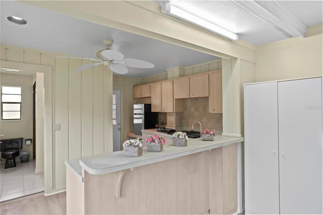 kitchen with black fridge, light brown cabinetry, light hardwood / wood-style floors, a kitchen bar, and kitchen peninsula