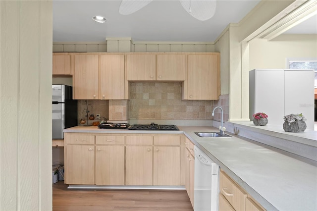 kitchen featuring stainless steel refrigerator, sink, dishwasher, light brown cabinetry, and light wood-type flooring