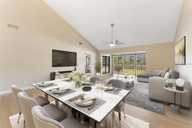 dining area with ceiling fan, high vaulted ceiling, and light hardwood / wood-style floors