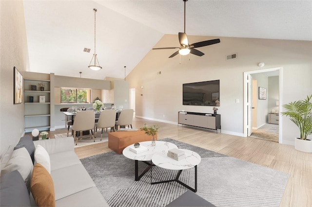 living room with ceiling fan, light hardwood / wood-style floors, and high vaulted ceiling