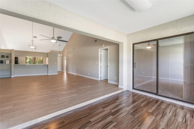 unfurnished living room featuring ceiling fan, vaulted ceiling, and hardwood / wood-style flooring