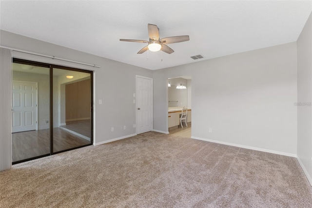 unfurnished bedroom featuring ceiling fan, light colored carpet, connected bathroom, and a closet