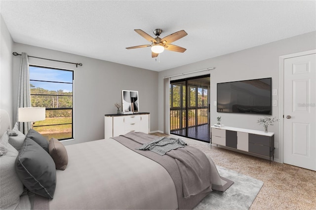 carpeted bedroom featuring ceiling fan, access to exterior, a textured ceiling, and multiple windows