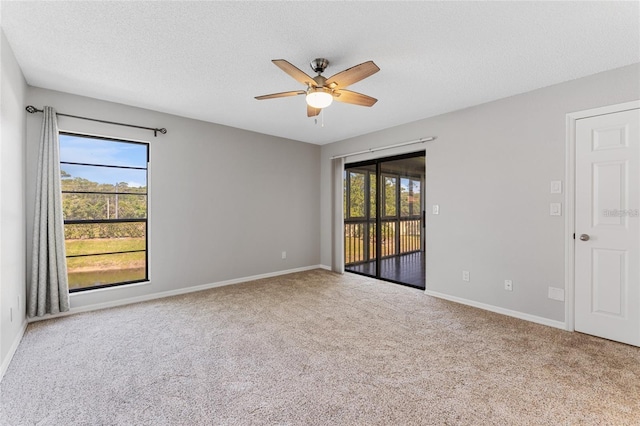 carpeted spare room with ceiling fan, plenty of natural light, and a textured ceiling