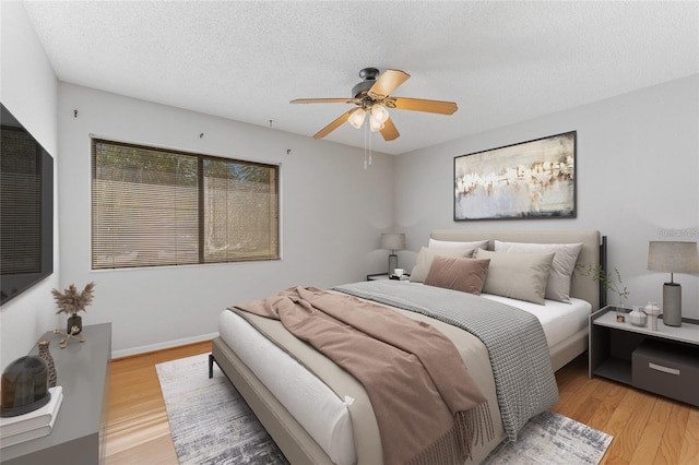 bedroom featuring a textured ceiling, light hardwood / wood-style floors, and ceiling fan