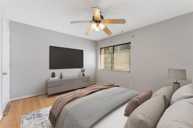 bedroom featuring ceiling fan, a textured ceiling, and light wood-type flooring