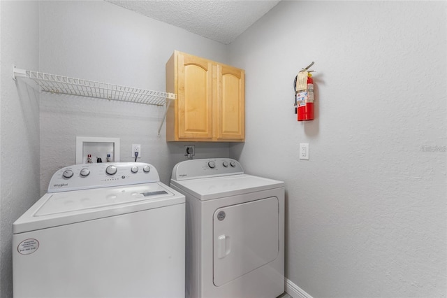 laundry room with washing machine and dryer, cabinets, and a textured ceiling